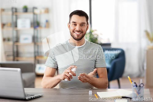 Image of man using hand sanitizer at home office