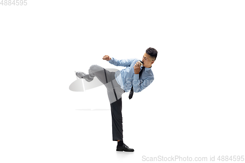 Image of Man in office clothes practicing taekwondo on white background. Unusual look for businessman in motion, action. Sport, healthy lifestyle.