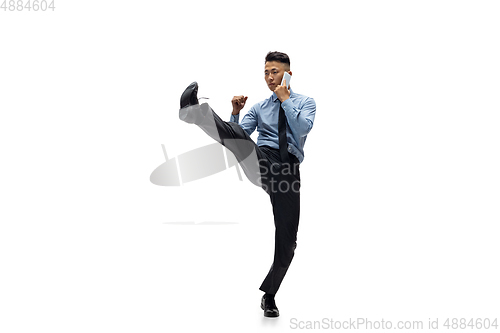 Image of Man in office clothes practicing taekwondo on white background. Unusual look for businessman in motion, action. Sport, healthy lifestyle.