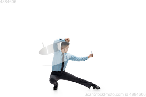 Image of Man in office clothes practicing taekwondo on white background. Unusual look for businessman in motion, action. Sport, healthy lifestyle.