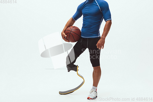 Image of Athlete with disabilities or amputee isolated on white studio background. Professional male basketball player with leg prosthesis training and practicing in studio.