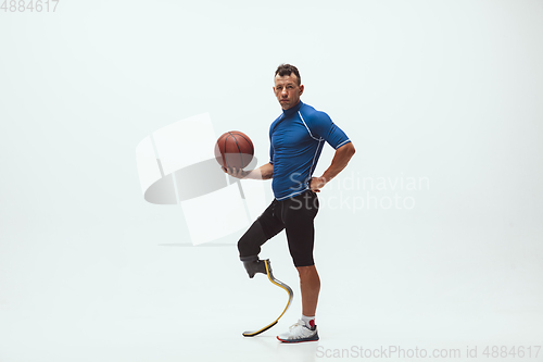 Image of Athlete with disabilities or amputee isolated on white studio background. Professional male basketball player with leg prosthesis training and practicing in studio.