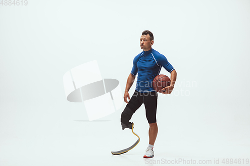 Image of Athlete with disabilities or amputee isolated on white studio background. Professional male basketball player with leg prosthesis training and practicing in studio.