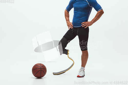 Image of Athlete with disabilities or amputee isolated on white studio background. Professional male basketball player with leg prosthesis training and practicing in studio.