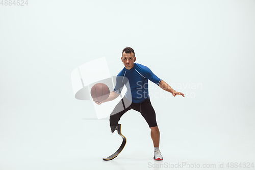 Image of Athlete with disabilities or amputee isolated on white studio background. Professional male basketball player with leg prosthesis training and practicing in studio.