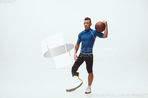 Image of Athlete with disabilities or amputee isolated on white studio background. Professional male basketball player with leg prosthesis training and practicing in studio.