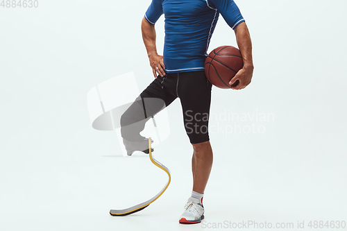 Image of Athlete with disabilities or amputee isolated on white studio background. Professional male basketball player with leg prosthesis training and practicing in studio.