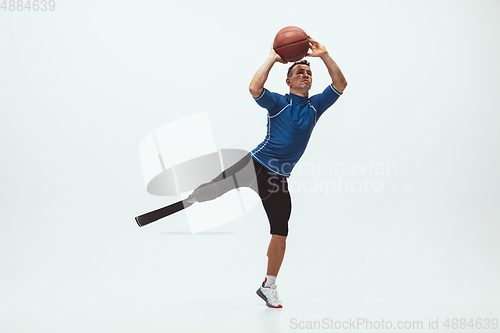 Image of Athlete with disabilities or amputee isolated on white studio background. Professional male basketball player with leg prosthesis training and practicing in studio.