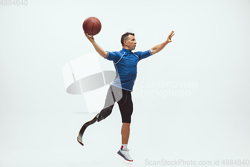 Image of Athlete with disabilities or amputee isolated on white studio background. Professional male basketball player with leg prosthesis training and practicing in studio.