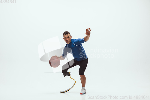 Image of Athlete with disabilities or amputee isolated on white studio background. Professional male basketball player with leg prosthesis training and practicing in studio.