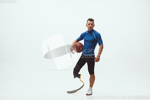 Image of Athlete with disabilities or amputee isolated on white studio background. Professional male basketball player with leg prosthesis training and practicing in studio.