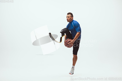 Image of Athlete with disabilities or amputee isolated on white studio background. Professional male basketball player with leg prosthesis training and practicing in studio.