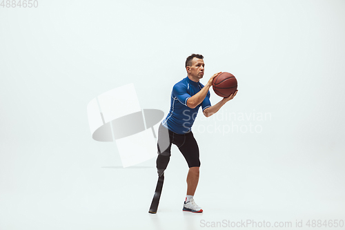 Image of Athlete with disabilities or amputee isolated on white studio background. Professional male basketball player with leg prosthesis training and practicing in studio.
