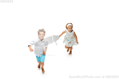 Image of Happy children, little caucasian boy and girl jumping and running isolated on white background