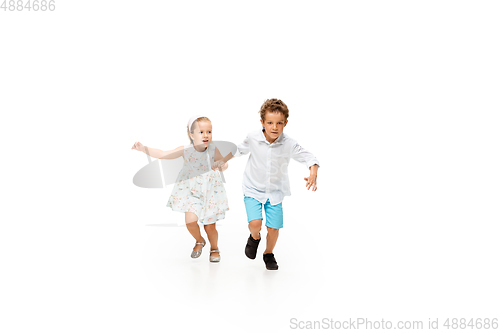 Image of Happy children, little caucasian boy and girl jumping and running isolated on white background