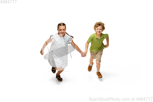 Image of Happy little caucasian girl and boy jumping and running isolated on white background