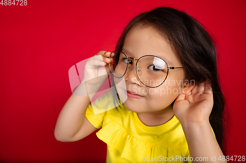 Image of Beautiful emotional little girl isolated on red background. Half-lenght portrait of happy child gesturing