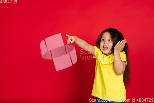 Image of Beautiful emotional little girl isolated on red background. Half-lenght portrait of happy child gesturing