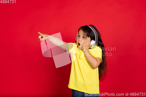 Image of Beautiful emotional little girl isolated on red background. Half-lenght portrait of happy child gesturing