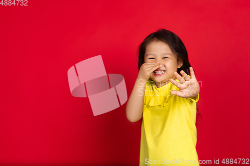 Image of Beautiful emotional little girl isolated on red background. Half-lenght portrait of happy child gesturing