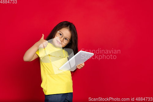 Image of Beautiful emotional little girl isolated on red background. Half-lenght portrait of happy child gesturing