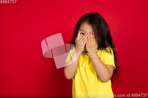 Image of Beautiful emotional little girl isolated on red background. Half-lenght portrait of happy child gesturing