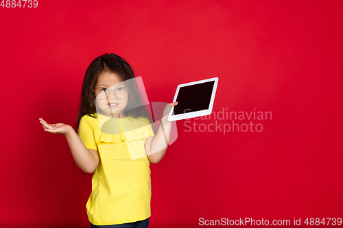 Image of Beautiful emotional little girl isolated on red background. Half-lenght portrait of happy child gesturing