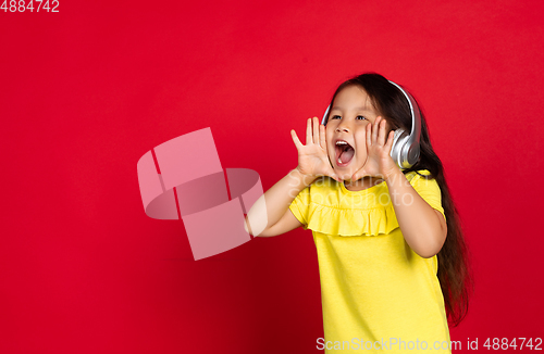 Image of Beautiful emotional little girl isolated on red background. Half-lenght portrait of happy child gesturing