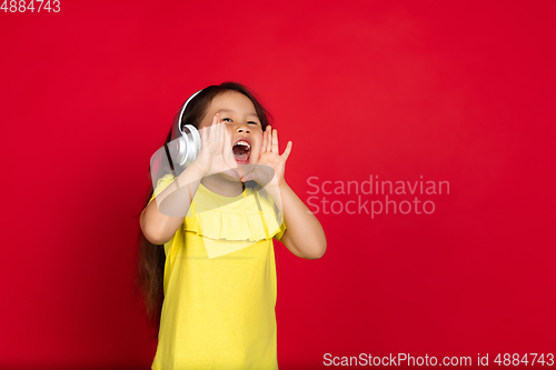 Image of Beautiful emotional little girl isolated on red background. Half-lenght portrait of happy child gesturing