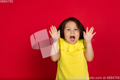 Image of Beautiful emotional little girl isolated on red background. Half-lenght portrait of happy child gesturing