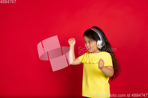 Image of Beautiful emotional little girl isolated on red background. Half-lenght portrait of happy child gesturing