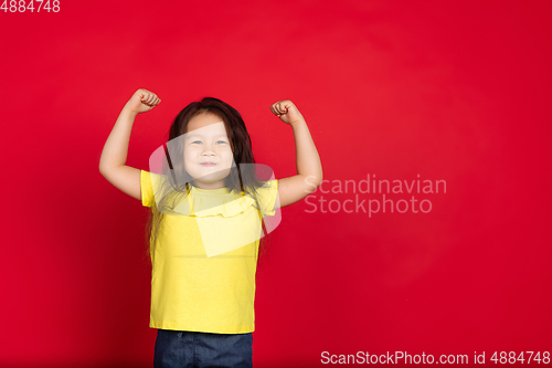 Image of Beautiful emotional little girl isolated on red background. Half-lenght portrait of happy child gesturing