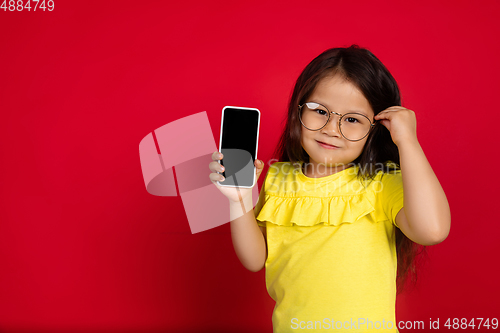 Image of Beautiful emotional little girl isolated on red background. Half-lenght portrait of happy child gesturing