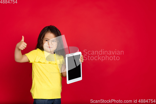 Image of Beautiful emotional little girl isolated on red background. Half-lenght portrait of happy child gesturing