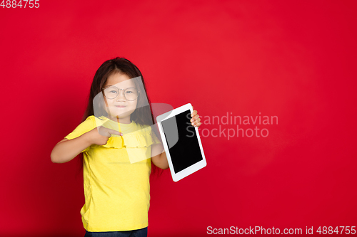 Image of Beautiful emotional little girl isolated on red background. Half-lenght portrait of happy child gesturing