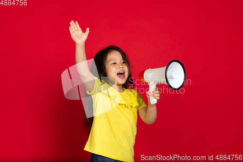 Image of Beautiful emotional little girl isolated on red background. Half-lenght portrait of happy child gesturing