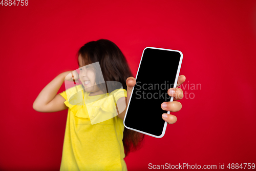 Image of Beautiful emotional little girl isolated on red background. Half-lenght portrait of happy child gesturing