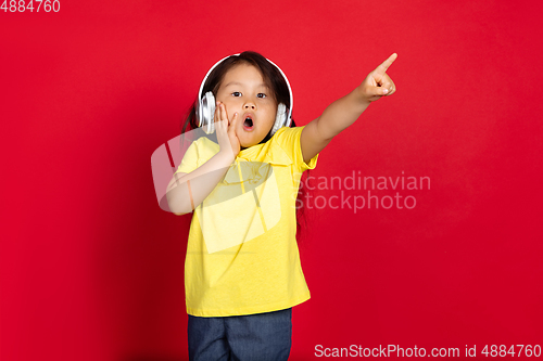 Image of Beautiful emotional little girl isolated on red background. Half-lenght portrait of happy child gesturing