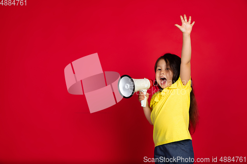 Image of Beautiful emotional little girl isolated on red background. Half-lenght portrait of happy child gesturing