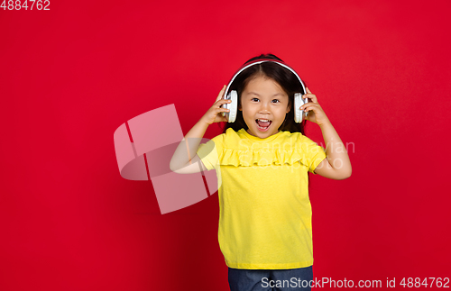 Image of Beautiful emotional little girl isolated on red background. Half-lenght portrait of happy child gesturing