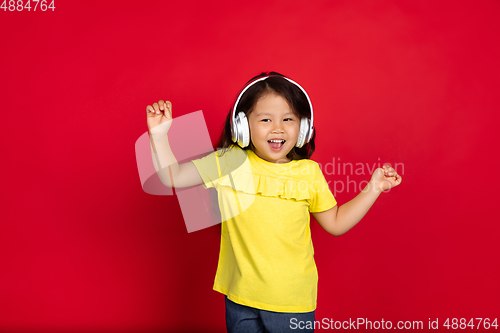 Image of Beautiful emotional little girl isolated on red background. Half-lenght portrait of happy child gesturing