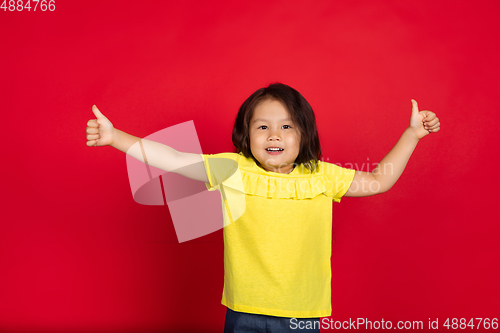Image of Beautiful emotional little girl isolated on red background. Half-lenght portrait of happy child gesturing
