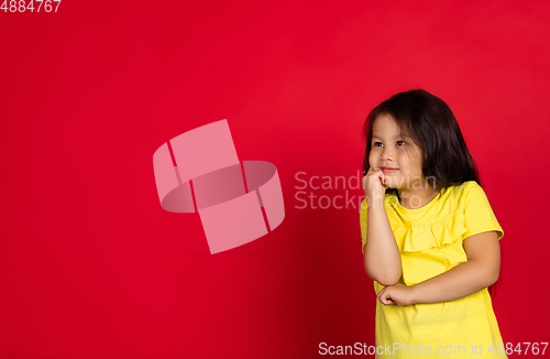 Image of Beautiful emotional little girl isolated on red background. Half-lenght portrait of happy child gesturing