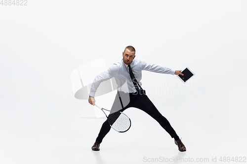 Image of Time for movement. Man in office clothes plays tennis isolated on white studio background.