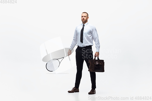 Image of Time for movement. Man in office clothes plays tennis isolated on white studio background.