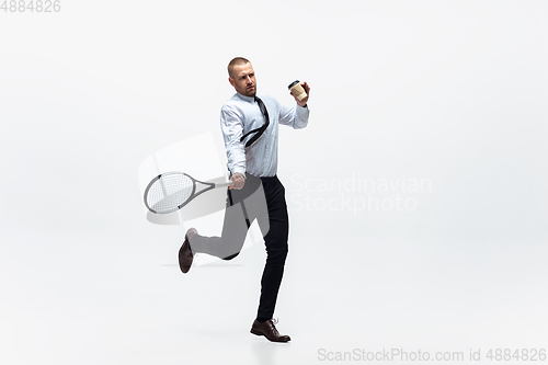 Image of Time for movement. Man in office clothes plays tennis isolated on white studio background.