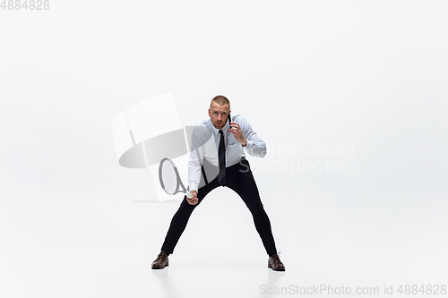 Image of Time for movement. Man in office clothes plays tennis isolated on white studio background.