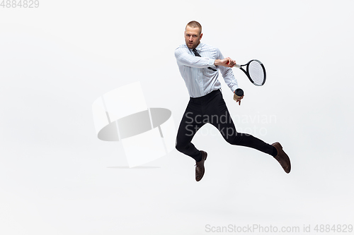 Image of Time for movement. Man in office clothes plays tennis isolated on white studio background.