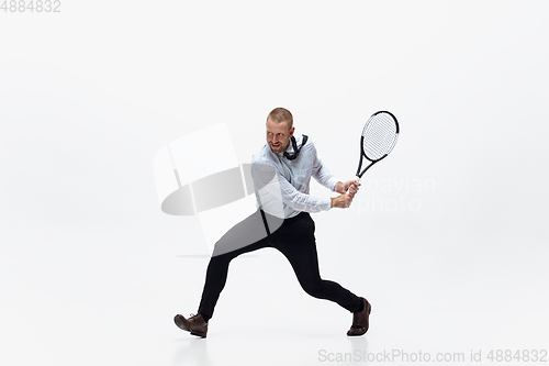 Image of Time for movement. Man in office clothes plays tennis isolated on white studio background.