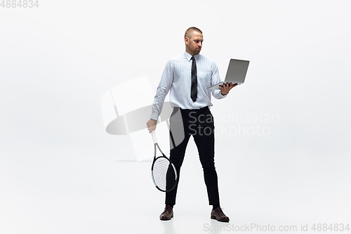 Image of Time for movement. Man in office clothes plays tennis isolated on white studio background.